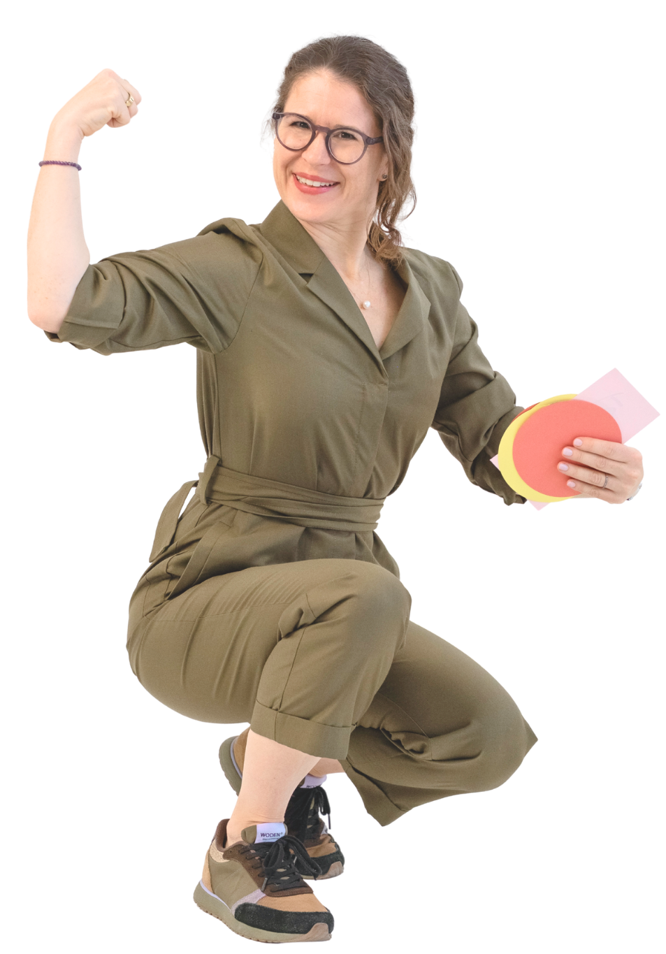 Salome Keller, Psychologin und Organisationsentwicklerin Salome Keller im olivgrünen Overall, hockt lächelnd mit Post-its in der Hand und spannt den Oberarm an