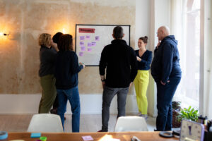 Salome Keller moderiert einen Workshop zur UX-Maturity, Teilnehmende von hinten vor einer Metaplanwand mit Post-its